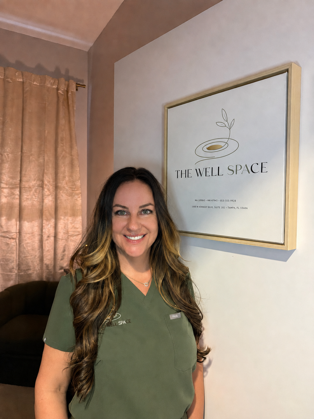Mandy Simpson, licensed massage therapist and owner of The Well Space, in the studio wearing olive scrubs.